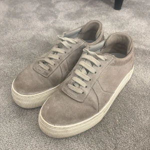 Beige sneakers från Axel Arigato - Snygga beige sneakers från Axel Arigato i mocka. Har inte kvar lådan de kom i