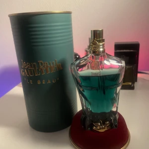 Jean Paul Gaultier Le Beau  - Säljer en Jean Paul Gaultier Le Beau Eau de Toilette i en unik flaska formad som en manlig torso. Parfymen har en fräsch och sensuell doft med noter av bergamott, kokosnöt och tonkaböna. Flaskan innehåller 75 ml och kommer i en elegant grön metallförpackning. Ca 5ml använt.