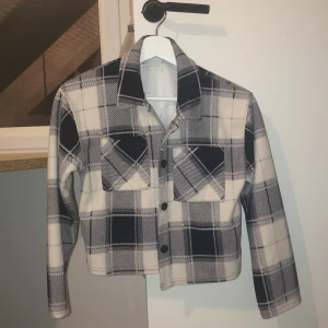 Rutig jacka från KappAhl - Säljer en super fin cardigan kofta från KappAhl i svart och beige.Använde den mycket förut men har växt ur den. Jackan har en klassisk krage och knappar framtill. Perfekt för en stilren look.