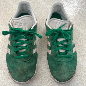 Gröna Adidas Gazelle sneakers - Snygga gröna Adidas Gazelle. Är lite sönder under skon på båda men det märks inte. Sulan på båda skona kan behövas bytas lite söder uppe på sulan. Annars är det en jättefin sko.