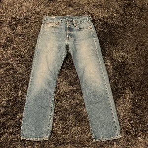 Blå jeansbyxor - Säljer ett par klassiska blå jeansbyxor från Levi's med en straight passform. De har en midwaist design och är tillverkade i jeansmaterial. Perfekta för en avslappnad stil.