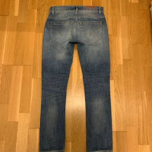 Blå jeans från Dondup - Säljer ett par snygga blå jeans från Dondup i modellen George. De har en skinny fit och är i bra skick. Jeansen har en klassisk femficksdesign med dragkedja och knapp. Perfekta för både vardag och fest🍾! Priset går att diskutera vid snabbt köp!