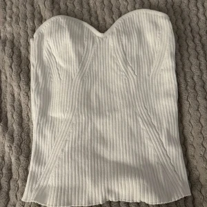 Vit ribbad tubtopp - Snygg vit tubtopp med ribbad struktur och hjärtformad urringning. Perfekt för en stilren look. Storlek S men lite stor i storleken