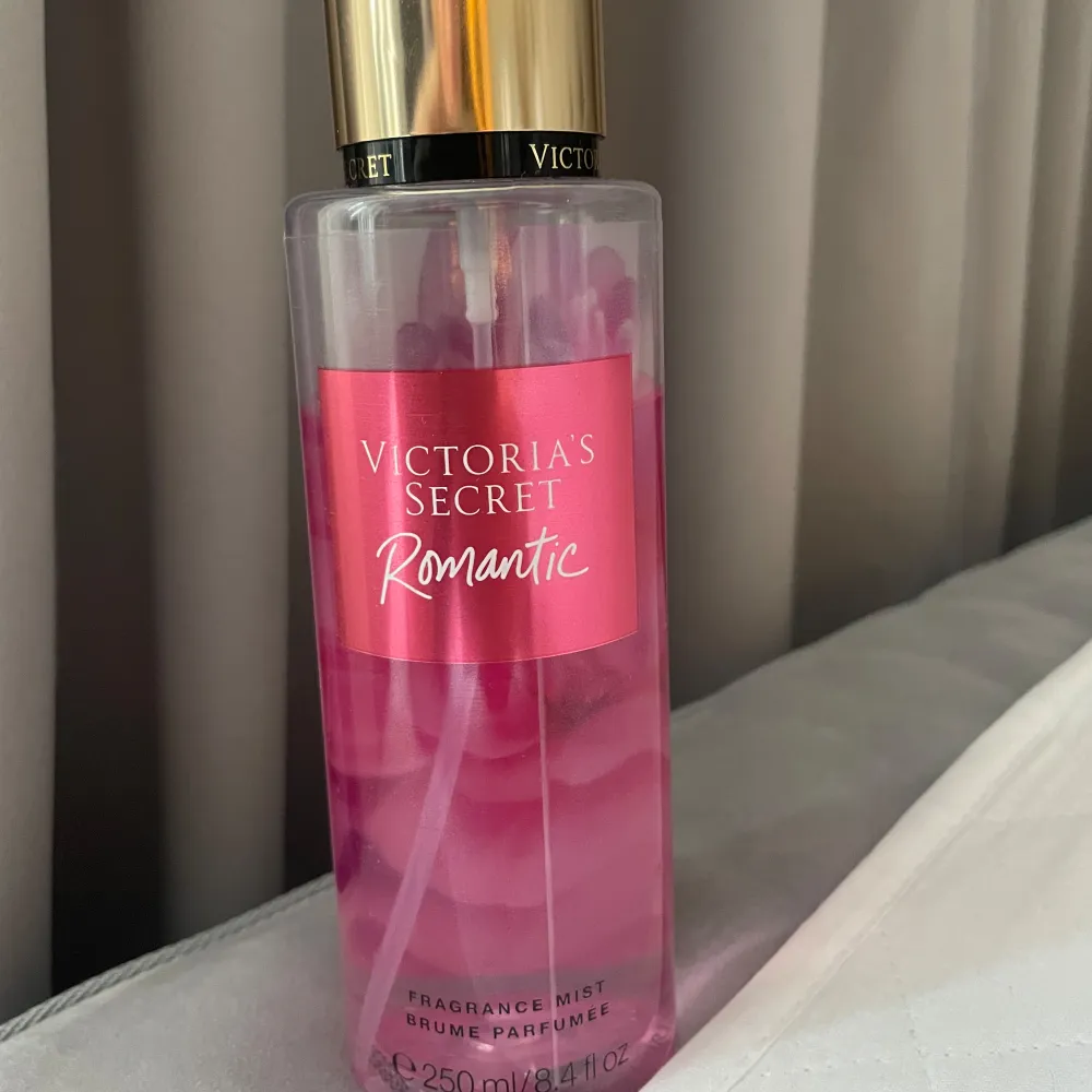 Säljer en Victoria's Secret Romantic Fragrance Mist. Flaskan är genomskinlig med en rosa etikett och har en guldig kork. Doften är en mix av rosa blomblad och mjuk mysk. Perfekt för en romantisk kväll eller när du bara vill känna dig extra speciell. Innehåller 250 ml.. Parfym.