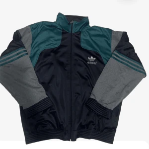 Adidas tröja - Snygg svart och grön jacka från Adidas med dragkedja och ribbade muddar. Jackan har långa ärmar och ett stort Adidas-logotyp på ryggen. Perfekt för en sportig look. Pris kan diskuteras såklart.🙌👏