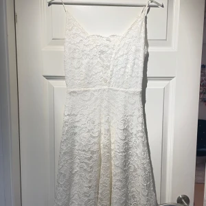 Vit spetsklänning från Model Behaviour - Elegant vit klänning i spets från Model Behaviour. Klänningen har smala axelband och en vacker spetsdesign 