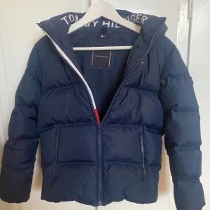 Mörkblå dunjacka från Tommy Hilfiger - Säljer en snygg och varm mörkblå dunjacka från Tommy Hilfiger!! Storlek 152 men passar mig som är XS. Köpt för 2000kr🙌