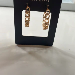 Guldiga örhängen  - Snygga guldiga örhängen från Montini/Glitter. Helt nya. 