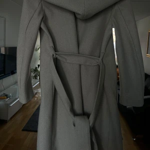 Beige grå kappa från Zara - Elegant grå kappa från Zara med knytbälte i midjan. Perfekt för kyligare dagar med sin stilrena design och långa ärmar. En klassisk och tidlös modell som passar till många tillfällen. Den är liten på mig därav sälja den mycket bra skick nypris 1000