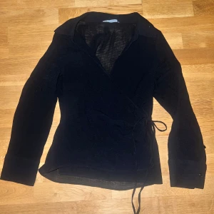 Svart omlottopp skjorta i linne material  - Snygg svart omlottopp med knytning i midjan.