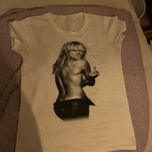 Vit t-shirt med Britney Spears tryck - Säljer en vit t-shirt med ett coolt tryck av Britney Spears på framsidan. T-shirten är kortärmad och passar storlek xs/s. Perfekt för en avslappnad stil eller att bära på en fest. Materialet känns mjukt och bekvämt. Små skandaler, inget man tänker på ☺️