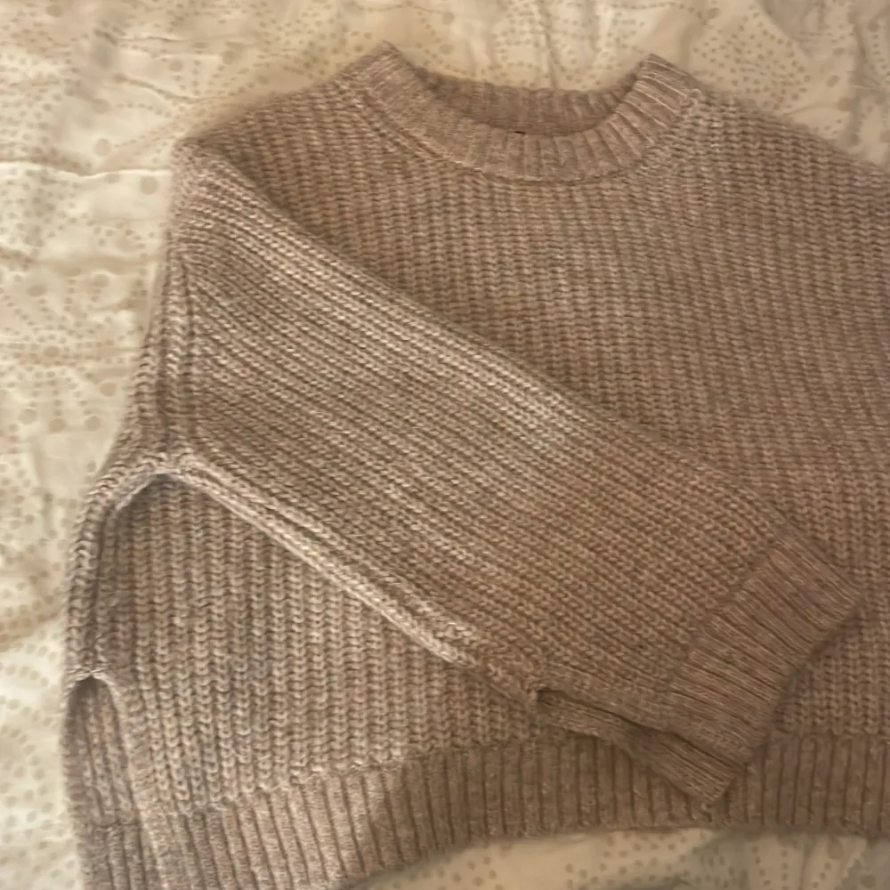 Nypris 699kr men säljs för 300kr. Mysig beige stickad tröja i ribbat material. Perfekt för kyliga dagar med sin avslappnade passform och långa ärmar. Den har en klassisk rund hals och är superbekväm att bära. Passar perfekt till både jeans och leggings!. Tröjor & Koftor.