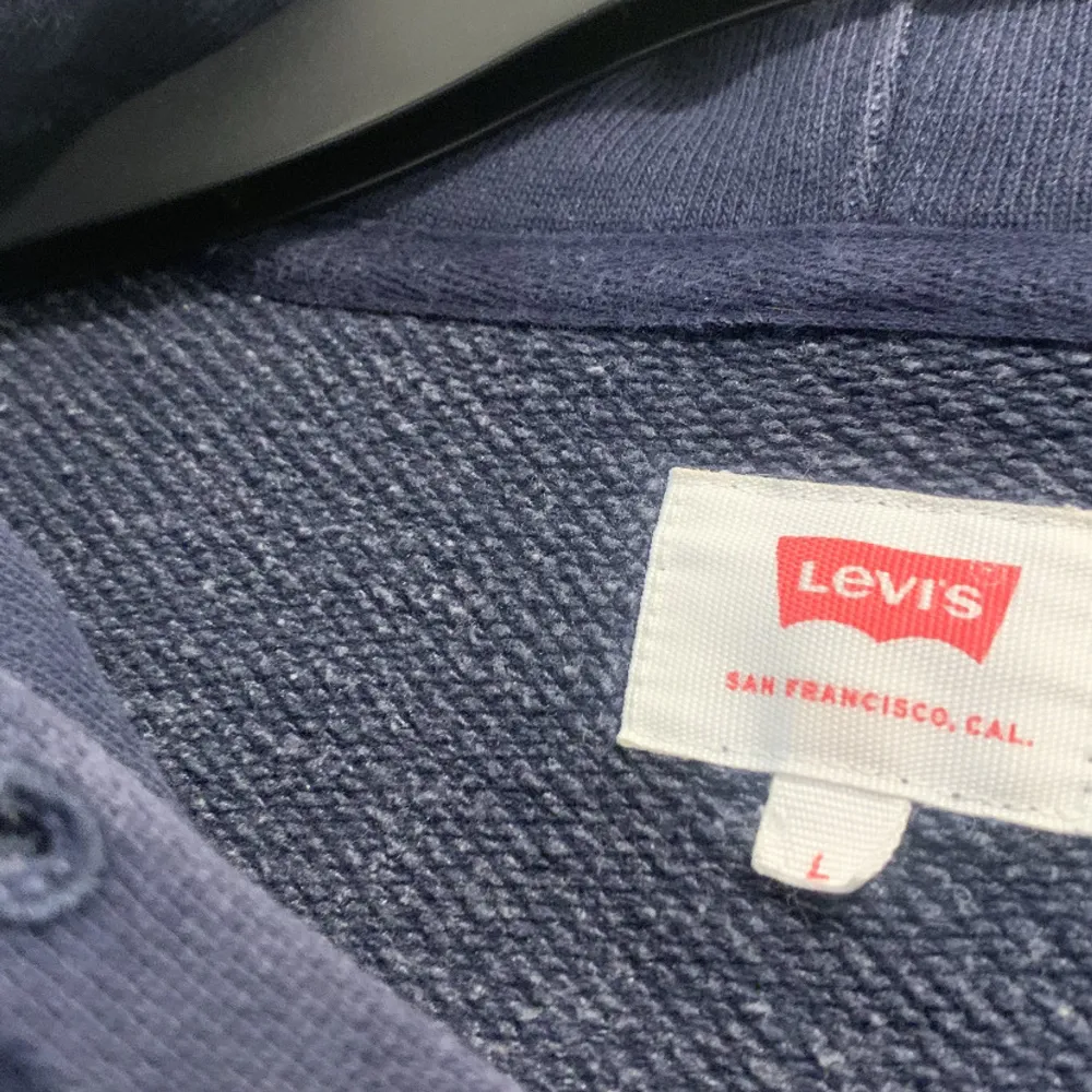 Säljer en snygg mörkblå hoodie från Levi's med den klassiska röda logotypen på bröstet. I storlek L/M  . Hoodies.