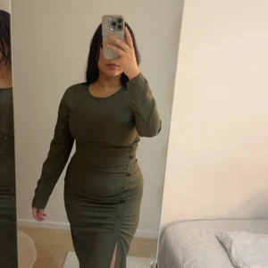 Grön långärmad klänning med slits - Snygg grön klänning med lång ärm och en stilren slits framtill. Perfekt för en elegant look.