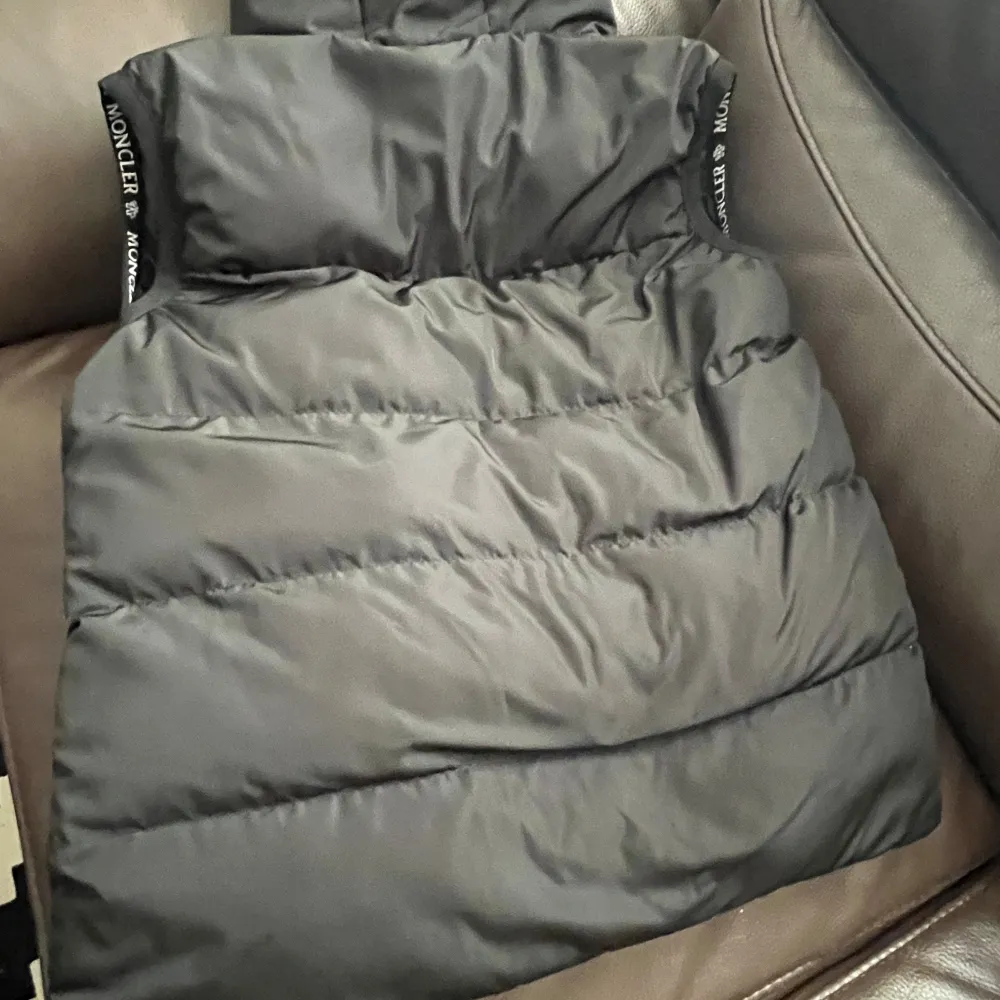 Säljer en snygg svart dunväst från Moncler i mycket bra skick. Västen har en stilren design med dragkedja och Moncler-logga på bröstet. Perfekt för höst och vår när du vill hålla värmen utan att bli för varm. Passar både till vardags och lite finare tillfällen.. Jackor.