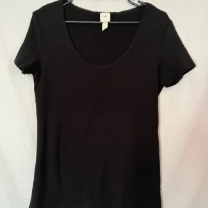 Svart t-shirt från H&M - Säljer en klassisk svart t-shirt från H&M i storlek L. Den har en rund halsringning och korta ärmar, perfekt för vardagsbruk. Materialet är mjukt och bekvämt, vilket gör den till ett bra basplagg i garderoben. Passar till alla tillfällen!