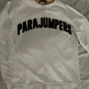 Vit sweatshirt från Parajumpers - Säljer en stilren vit sweatshirt från Parajumpers med svart text på bröstet. Tröjan har långa ärmar och en rund halsringning.  Storlek S