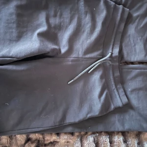 Svarta mjukisbyxor med snörning - Säljer ett par svarta mjukisbyxor med snörning i midjan. Perfekta för en avslappnad stil och bekväma att bära. De har en enkel design utan mönster.