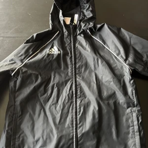 Vindjacka adidas - Säljer nu denna snygga vindjackan från adidas. Den är perfekt nu till våren och höst och även perfekt till ex. Fotbollsträningar. Den är aldrig använd. Köpt för mer än ett år sen. Skulle säga att nypris ligger mellan 600-800kr. Priset är inte hugget i sten, skicka gärna prisförslag. Mvh LuxeNest. (Strl L barn strl)