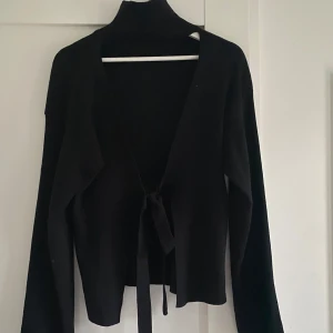 Svart polotröja  - Svart polotröja med knytning baktill. 