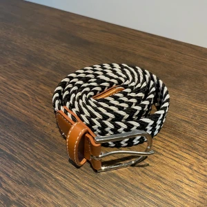 Svartvitt mönstrat bälte - Snyggt svartvitt bälte med zigzag-mönster. Perfekt för att ge din outfit en cool touch. Bältet har en stilren design och är lätt att matcha med olika kläder. FRÅN ONEWEAR