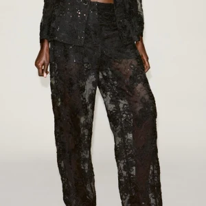 Svarta spetsbyxor med blommönster - Eleganta svarta byxor i spets med ett vackert blommönster. Byxorna har en loose passform och är perfekta för en stilfull look. De är högmidjade och har en transparent design som ger en unik touch. Helt oanvända med prislapp kvar💗 nypris 560kr