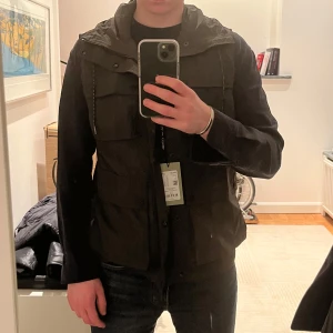 Grön väst från Marc O’Polo  - Otroligt unik och snygg grön väst från Marc O’Polo med huva och dragkedja. Lappen finns kvar och den är helt oanvänd. Pris kan diskuteras!