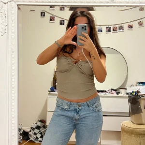 Beige ribbad bandeau  - Säljer en snygg beige ribbad linnetopp med en unik knytdetalj framtill. Toppen är ärmlös och har en tight passform som framhäver figuren. Perfekt för en stilren och trendig look.