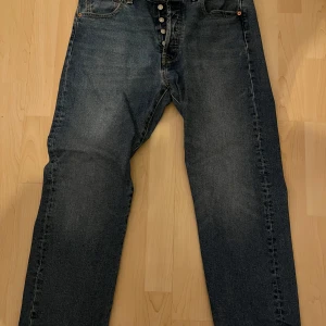Levi's 501 jeans - Klassiska Levi's 501 jeans i en mörkblå färg. De har en knappgylf och raka ben. Perfekta för en avslappnad stil och har den ikoniska läderpatchen baktill. Jeansen är mer åt det baggy hållet.