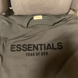 Svart t-shirt från Fear of God Essentials - Snygg svart t-shirt från Fear of God Essentials med tryck på bröstet. Perfekt för en stilren och avslappnad look.