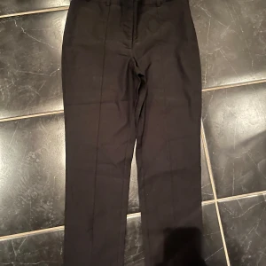 Svarta kostymbyxor från JDY - Snygga svarta kostymbyxor från JDY med slits där nere💕. Byxorna har en rak passform . De har en knapp och dragkedja framtill för enkel stängning.