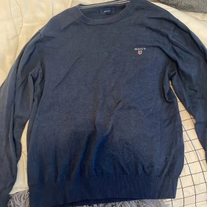 Mörkblå tröja från GANT - Säljer en snygg mörkblå tröja från GANT i storlek M. Tröjan är perfekt i skick 10/10 . Den är perfekt för både höst och vinter och har en liten GANT-logga på bröstet. Materialet känns mjukt och bekvämt, perfekt för en stilren vardag.