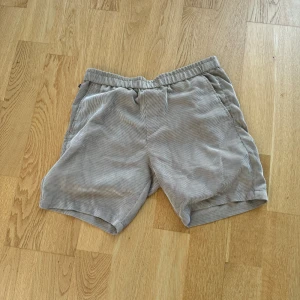 Grå randiga shorts - Säljer ett par beige randiga shorts i mjukt material. De har en elastisk midja för extra komfort och två sidofickor. Dom är från matinique och storlek M