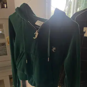 Säljer en superfin grön hoodie från Juicy Couture i storlek XXS. Den är gjord i mjuk velour och har en dragkedja framtill. På baksidan finns det glittriga 'Juicy'-text och på framsidan ett glittrigt emblem. Perfekt för en chill dag eller när du vill känna dig extra glam!