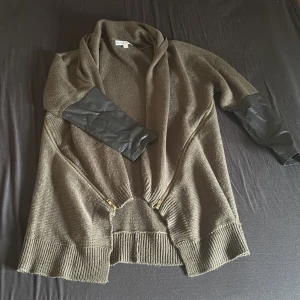 Olivgrön kofta från Divine Heart - Säljer en supermysig olivgrön kofta från Divine Heart. Den är stickad och har en avslappnad passform med långa ärmar. Koftan har snygga dragkedjedetaljer framtill och en mjuk krage. Perfekt för höst och vinter när du vill hålla dig varm och stilren. 🧥✨