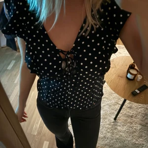 Prickig blus  - Jätte fin prickig blus, med volanger på axlar och fram. Sparsamt använd.
