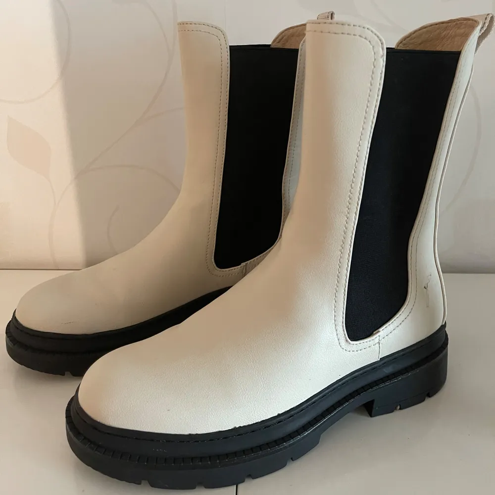 Säljer ett par snygga vita chelsea boots i skinn med svarta detaljer på sidorna ifrån märket Tamaris. De har en robust svart sula som ger bra grepp. Perfekta för både höst och vår! Använda ett fåtal gånger. Nypris: 900kr🍂🍁. Skor.