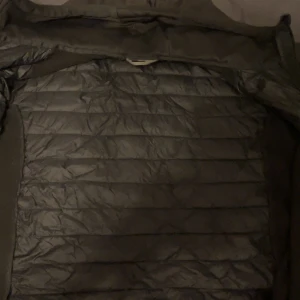 Svart quiltad jacka från McKinley - Säljer en svart quiltad jacka från McKinley i storlek XL. Jackan har en dragkedja och en luva. Använd fåtal gånger och väldigt bekväm. Pris är diskuterbart. 