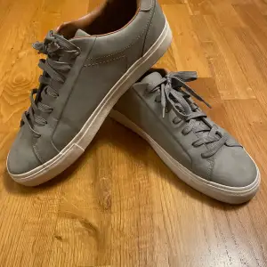 Säljer ett par stilrena grå sneakers från Zara. De har en snygg och enkel design med snörning och en vit sula. Passar till det mesta i garderoben. Säljer då jag inte de inte används längre, använder mer sportiga skor. Har haft de ungefär 1 år, men har nog inte använt de mer än 5 gånger. Kan tvätta den vita sulan renare innan jag skickar iväg de om det önskas. Pris går att diskuteras, ställ gärna frågor!