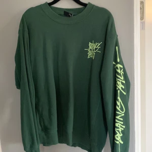 Grön oversized tröja från H&M - Säljer en grön oversized tröja från H&M med coolt tryck i neon på bröstet och ärmen. Perfekt för en avslappnad stil och passar bra till både jeans och joggers. Tröjan är i bra skick och superbekväm att ha på sig. Perfekt för höst och vår!