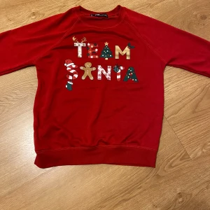 Röd jultröja från FB Sister - Säljer en superfin röd jultröja från FB Sister i storlek XXS. Den har texten 'Team Santa' i olika juliga mönster och färger. Perfekt för julmys och att sprida julstämning! Tröjan är långärmad och gjord i ett mjukt material. Pris kan diskuteras.