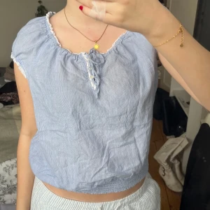 Ljusblå randig blus - Säljer en söt ljusblå blus med tunna vita ränder. Den har korta ärmar och en liten knytning framtill. Perfekt för sommardagar! 💙