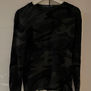 Camouflage tröja från Polo Ralph Lauren - Säljer en snygg camouflage tröja från Polo Ralph Lauren. Den är i mörka nyanser och har ett diskret broderat märke på bröstet. Perfekt för en casual look och passar bra till både jeans och chinos. Tröjan är långärmad och i mycket bra skick. Storleken Är i L men sitter mer som XS/S