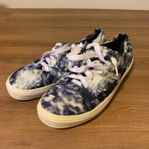 Blå och vita sneakers med batikmönster/himmel Åhlens - Säljer ett par coola sneakers i blått och vitt med ett unikt batikmönster från Åhlens.  Den vänstra sulan har blivit lite gul (kolla på de sista 2 bilderna) men det syns knapt, trot att det kan också tas bort