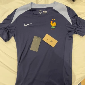 Blå fotbollströja från Nike - Säljer en sprillans ny uppvärmnings tröja från franska landslaget i storlek ”S”. Den är aldrig använd och borde passa perfelt till en varm sommardag💙