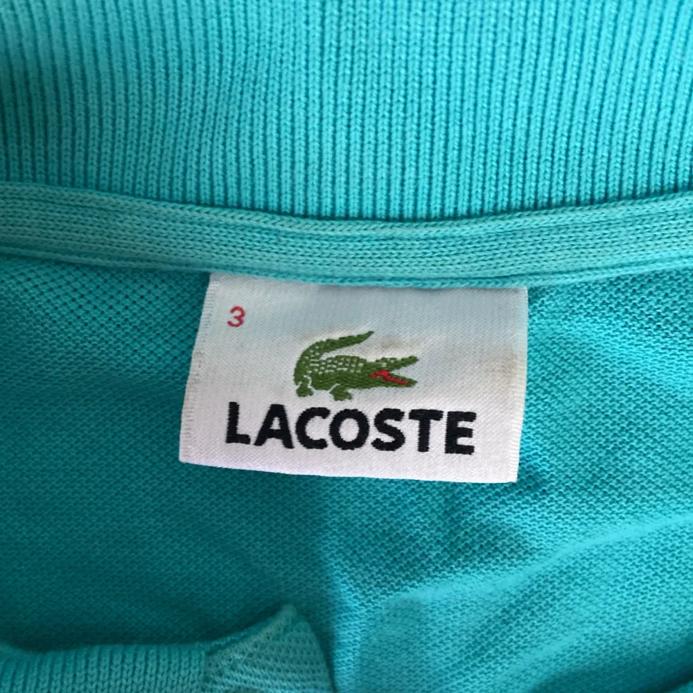 Säljer en snygg turkos pikétröja från Lacoste. Den har den klassiska krokodilloggan på bröstet och tre knappar vid halsen. Perfekt för en avslappnad men stilren look. Passar både till vardags och lite finare tillfällen. 🐊. Tröjor & Koftor.