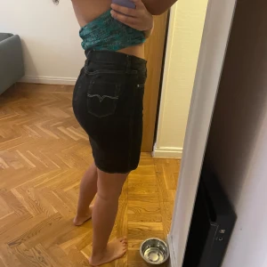 Svart jeanskjol från Gul & Blå - Säljer en snygg svart jeanskjol från Gul & Blå. Kjolen är i en klassisk femficksmodell med en tight passform som sitter perfekt. Den är gjord i slitstarkt denim och har en stilren design som passar till allt. Perfekt för både vardag och fest!