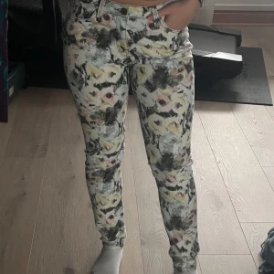 Mönstrade jeans från Lee - Snygga mönstrade jeans från Lee med ett unikt blommigt mönster i flera färger. Byxorna har en klassisk femficksdesign och dragkedja. Perfekta för dig som vill sticka ut med en färgglad stil.