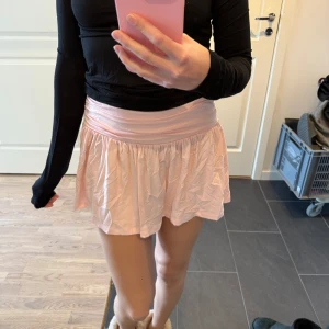 Ljusrosa kortkjol - Säljer en söt ljusrosa kortkjol med en bred midja som ger en bekväm passform. Kjolen har en lätt och luftig design, perfekt för varmare dagar. Den är enkel att matcha med olika toppar och accessoarer.