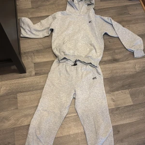 Grå hoodie med NYC-tryck - Säljer en grå hoodie med trycket 'NYC' på bröstet. Tröjan har en bekväm passform med långa ärmar och en praktisk huva. Perfekt för en avslappnad stil.